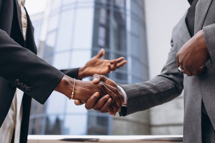 Poignée de main entre professionnels devant des immeubles de bureaux
