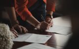 Deux personnes signent des documents contractuels à une table